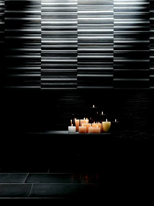 Stimmungsvolles Bad mit schwarzen Wandfliesen und Kerzenbeleuchtung